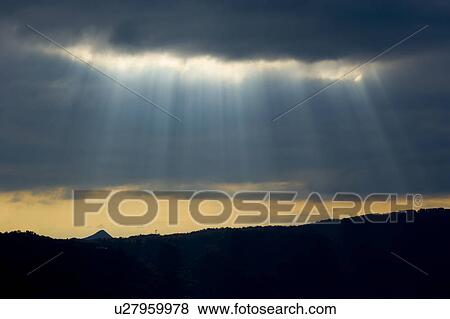 Stock Photo - Sunbeams Over Silhouetted Mountains. Fotosearch