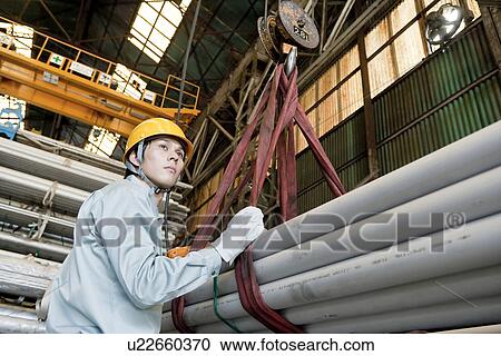Stock Image - Warehouse Worker Operating Pulley. Fotosearch