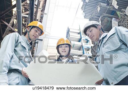 Stock Photo - Warehouse Workers Looking at Blueprint. Fotosearch