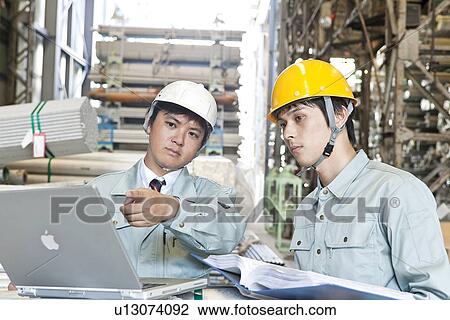 Stock Image - Warehouse Workers Using Laptop. Fotosearch