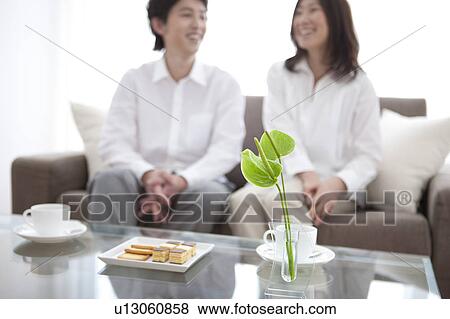 Stock Photo - Young couple relaxing on sofa drinking coffee. Fotosearch