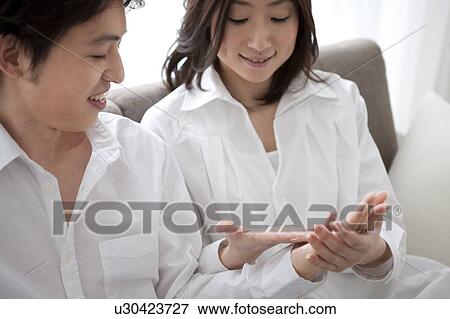 Young couple relaxing on sofa holding hands View Large Photo Image Stock Photo - Young couple relaxing on sofa holding hands. Fotosearch