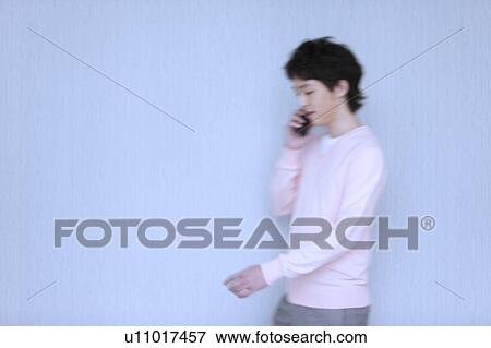 Young man walking and on cell phone View Large Photo Image Stock Photo - Young man walking and on cell phone. Fotosearch