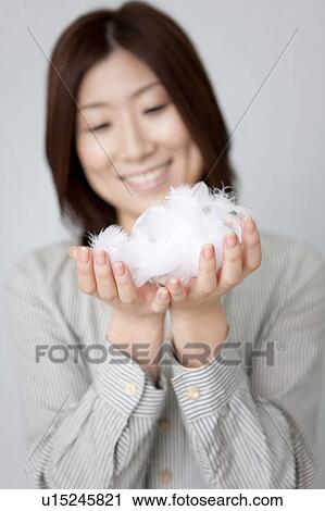 Stock Image - Young woman holding feathers. Fotosearch