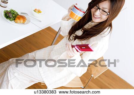 Young woman in pajamas drinking coffee and using cell phone View Large Photo Image Stock Image - Young woman in pajamas drinking coffee and using cell phone. Fotosearch