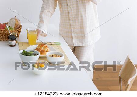 Stock Image - Young woman in pajamas holding a glass of orange juice. Fotosearch