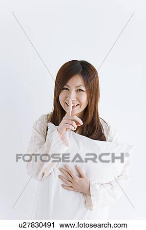 Stock Image - Young woman in pajamas holding a pillow. Fotosearch