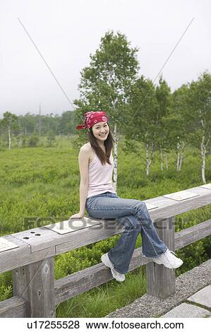 Stock Photo - Young Woman Sitting on Fence. Fotosearch