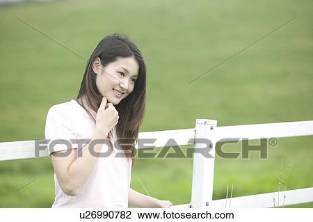 Stock Image - Young Woman Smiling in Field. Fotosearch