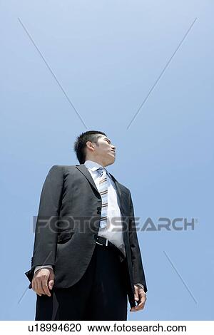 Stock Image - A businessman looking up at the sky. Fotosearch
