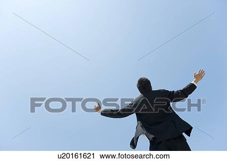 Stock Image - A businessman opening hands up to the sky. Fotosearch