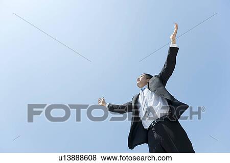 Stock Photo - A businessman opening hands up to the sky. Fotosearch