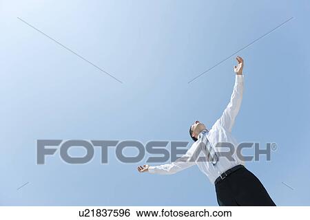 Stock Photograph - A businessman opening hands up to the sky. Fotosearch