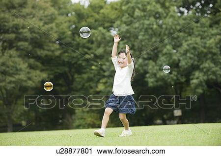 Stock Image - A girl chasing bubbles. Fotosearch