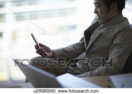 Stock Image - Businessman checking cell-phone. Fotosearch