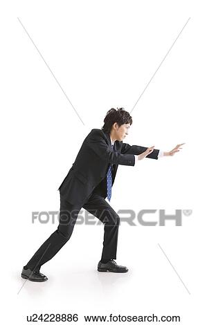 Businessman crouching as if he's pushing something View Large Photo Image Stock Photograph - Businessman crouching as if he's pushing something. Fotosearch