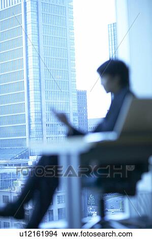 Picture - Businessman sitting in an office, Tokyo Prefecture, Honshu, Japan. Fotosearch