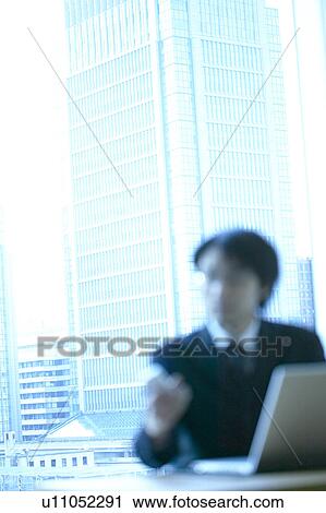 Stock Image - Businessman sitting in an office, Tokyo Prefecture, Honshu, Japan. Fotosearch