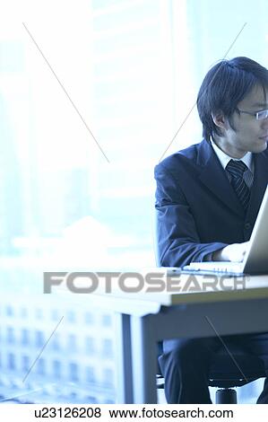 Stock Photo - Businessman sitting in an office, Tokyo Prefecture, Honshu, Japan. Fotosearch