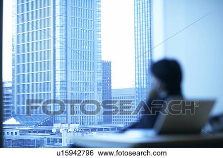 Stock Photograph - Businessman sitting in an office, Tokyo Prefecture, Honshu, Japan. Fotosearch