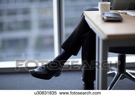 Stock Photography - Businessman sitting on chair, low section. Fotosearch