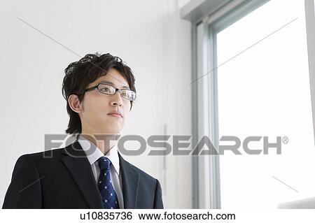 Businessman standing by the window View Large Photo Image Stock Photograph - Businessman standing by the window. Fotosearch