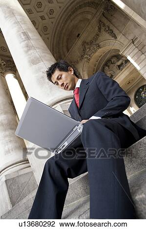 Stock Image - Businessman Using Laptop on Steps of Royal Exchange. Fotosearch