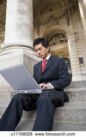 Stock Photo - Businessman Using Laptop on Steps of Royal Exchange. Fotosearch