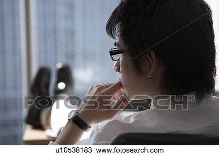 Stock Image - Businessman with feet up on desk. Fotosearch