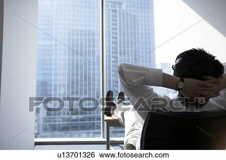 Stock Photograph - Businessman with feet up on desk. Fotosearch