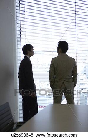 Stock Photo - Businessmen talking by the window. Fotosearch