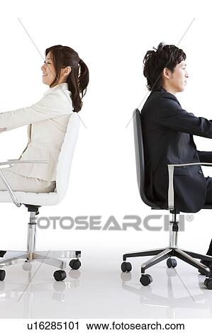 Stock Image - Businesspeople sitting on chair back to Back. Fotosearch