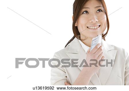 Stock Image - Businesswoman holding a cell phone and smiling. Fotosearch