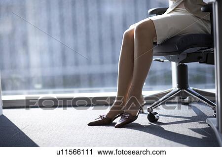 Stock Image - Businesswoman sitting on chair, low section. Fotosearch