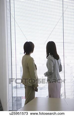 Businesswomen standing by the window View Large Photo Image Stock Image - Businesswomen standing by the window. Fotosearch