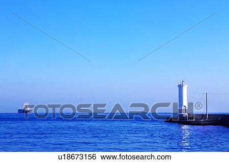 Stock Photograph - Cargo Ship Near Lighthouse. Fotosearch
