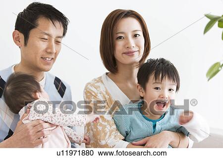 Stock Image - Family sitting on sofa. Fotosearch