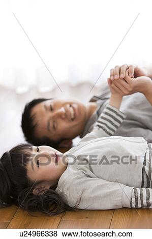 Stock Photo - Father and daughter lying on back on hardwood floor. Fotosearch