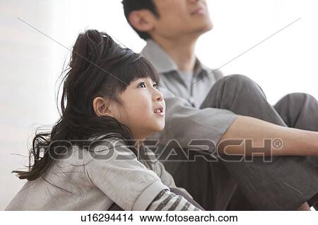 Picture - Father and daughter sitting on hardwood floor. Fotosearch