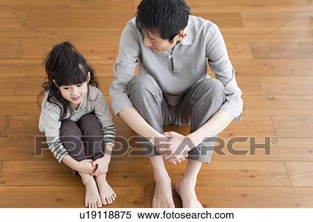 Stock Photography - Father and daughter sitting on hardwood floor. Fotosearch