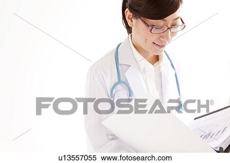 Female doctor looking at ring binder View Large Photo Image Stock Photography - Female doctor looking at ring binder. Fotosearch