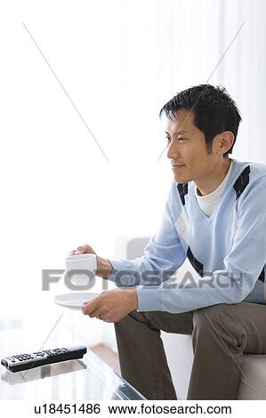 Stock Photograph - Man watching television and drinking coffee. Fotosearch