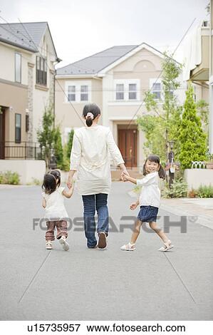 Stock Photo - Mother and daughters holding hands and walking. Fotosearch