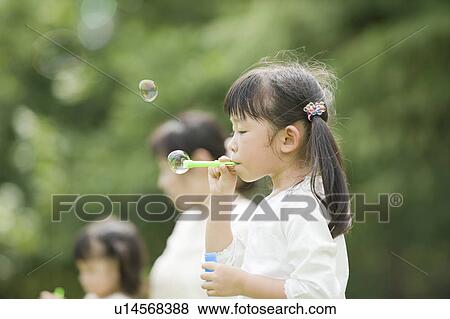 Stock Photo - Mother and daughters playing in the park. Fotosearch