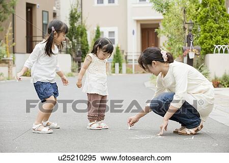 Stock Photography - Mother writing on street with chalk. Fotosearch