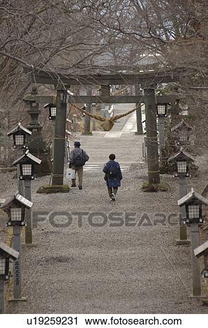 Stock Image - Old Couple Walking Through Torii Gate. Fotosearch