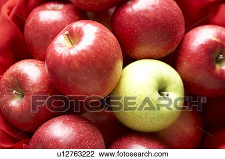 Stock Image - One green apple in red apples. Fotosearch