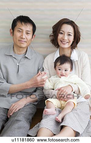 Stock Image - Portrait of family sitting on hardwood floor. Fotosearch