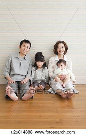 Stock Photo - Portrait of family sitting on hardwood floor. Fotosearch