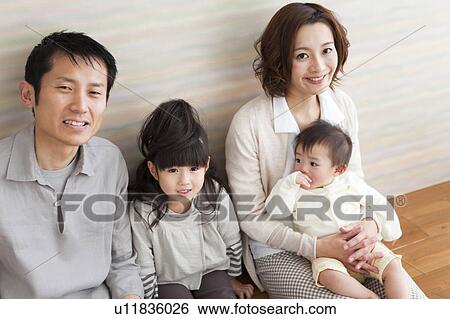 Stock Photograph - Portrait of family sitting on hardwood floor. Fotosearch